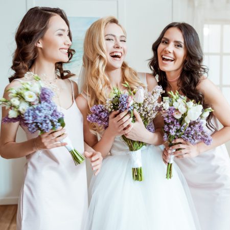 beautiful laughing bride with bridesmaids holding bouquets