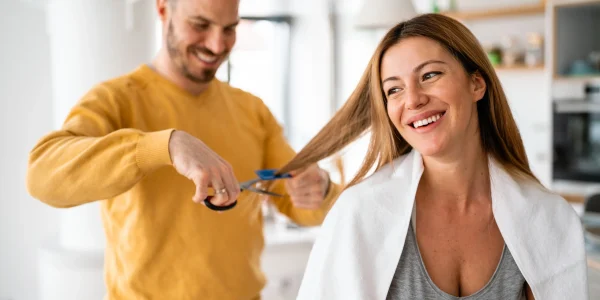 Hairdresser-cutting-her-of-a-beautiful-woman-at-home