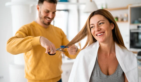 Hairdresser-cutting-her-of-a-beautiful-woman-at-home