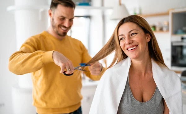 Hairdresser-cutting-her-of-a-beautiful-woman-at-home