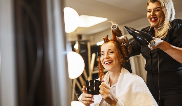 At hair salon hairdresser using hairdryer