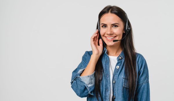 Young friendly caucasian woman IT support customer support agent hotline helpline worker in headset looking at camera while assisting customer client isolated in white background